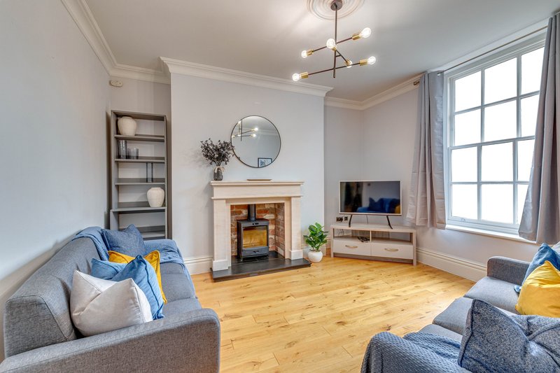 Spacious living room with two grey sofas, fireplace, wooden floor and large windows