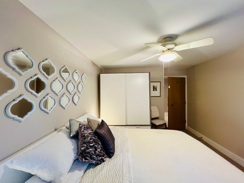Bedroom with double bed, decorative wall mirrors, ceiling fan and wardrobe