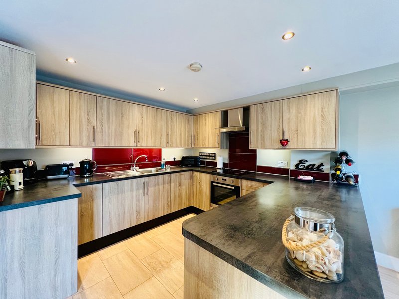 Modern kitchen with light wood cabinets, black countertops, island, and stainless steel appliances