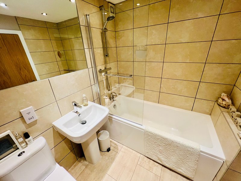 Bathroom with bathtub, shower enclosure, pedestal sink and tiled walls