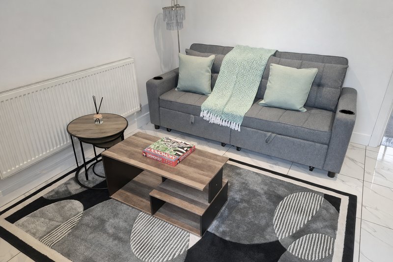 Modern living room with grey sofa, wooden coffee table, side table, cushions and area rug