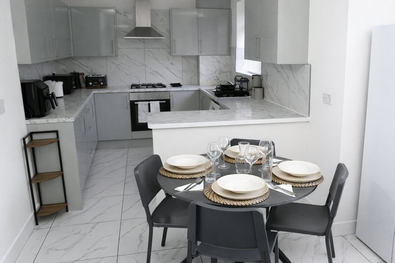 Modern kitchen with marble countertop and dining table set for four with place settings