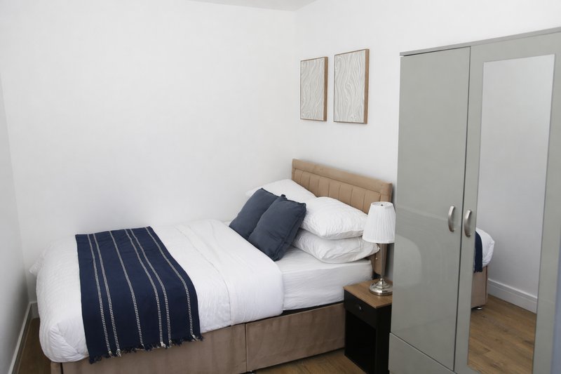 Bedroom with double bed, navy striped throw, white pillows and bedside table with lamp