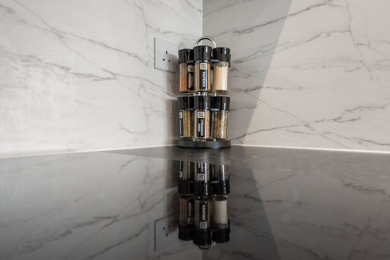 Corner of marble bathroom with wall-mounted organizer holding cosmetic and skincare products