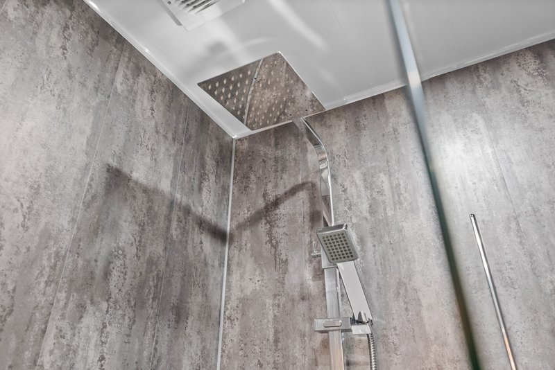 Modern bathroom shower with rainfall showerhead, gray tile walls and chrome fixtures