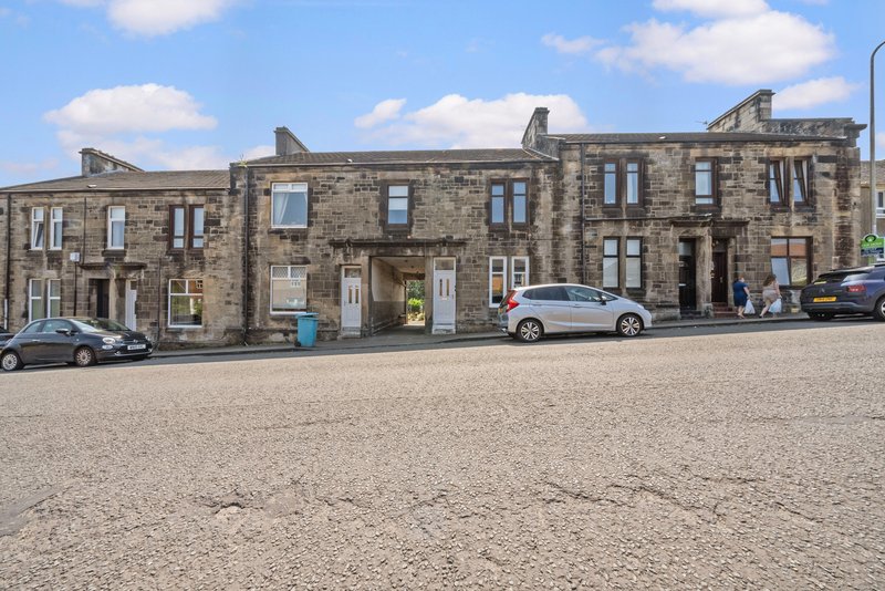 Stone terrace building with multiple residential units, parked cars, and street frontage