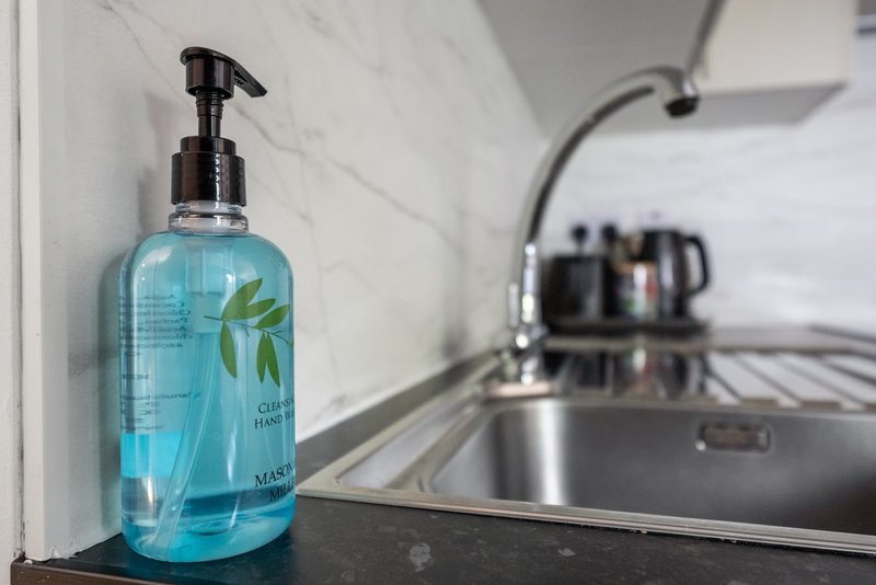 Kitchen sink with turquoise hand wash bottle and stainless steel tap