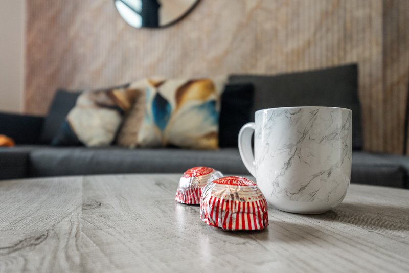 Living room with marble-patterned mug, cupcakes, and sofa with decorative cushions