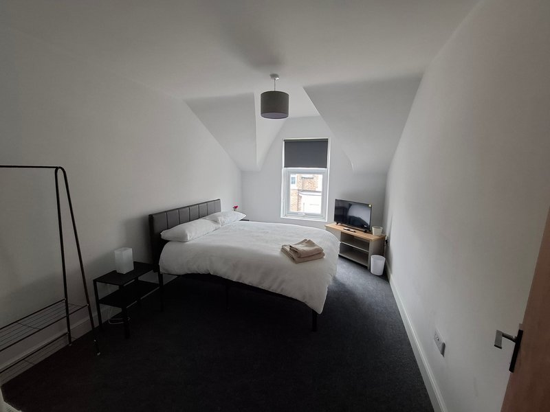 Bright attic bedroom with double bed, dark floor, skylight window and pendant lamp