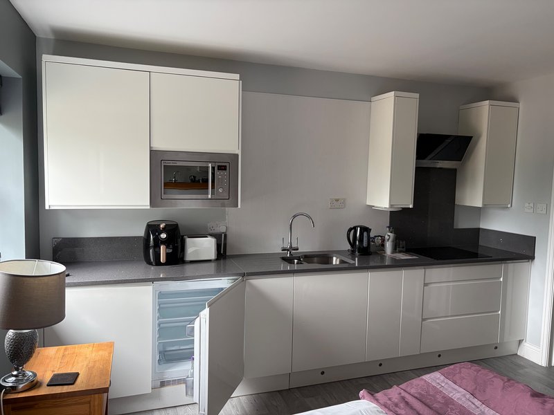 Modern kitchen with white cabinetry, black countertop, integrated appliances and dining area