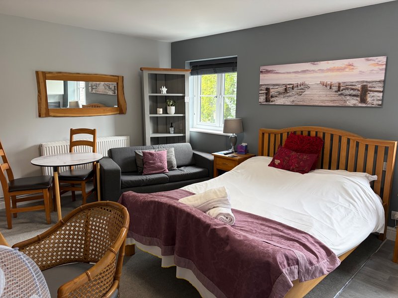 Studio bedroom with double bed, dining table, seating area and kitchenette