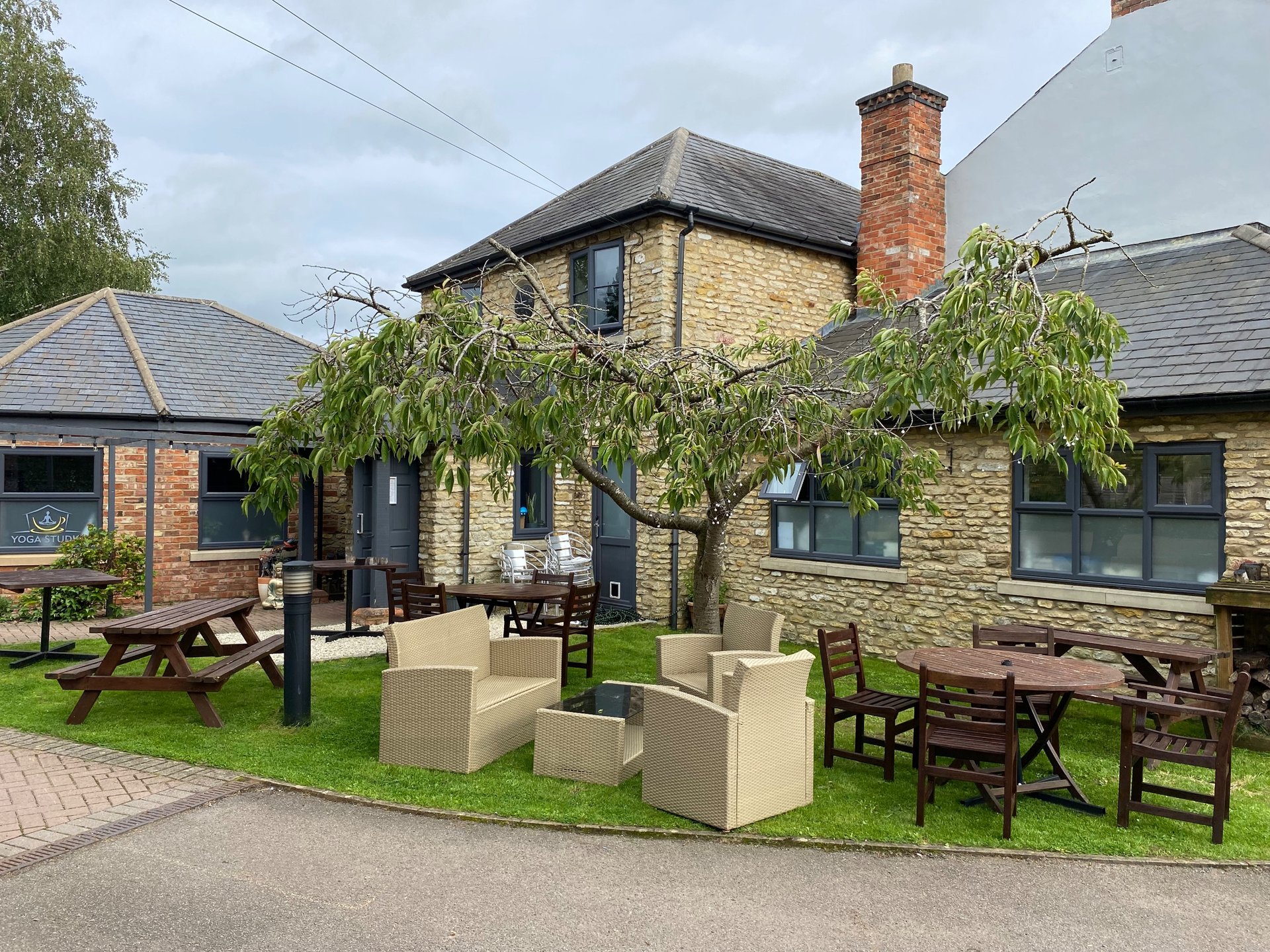 Stone cottage exterior with patio, picnic tables, garden furniture and tree