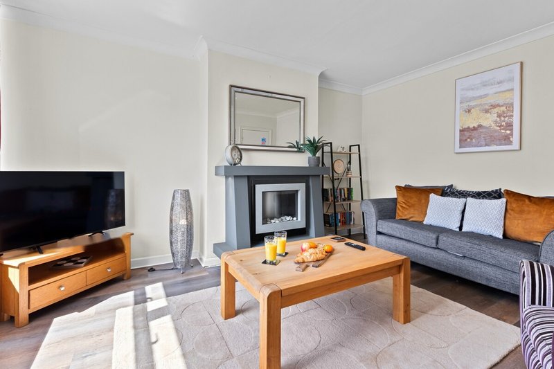 Bright living room with fireplace, wooden coffee table, blue sofa and TV unit
