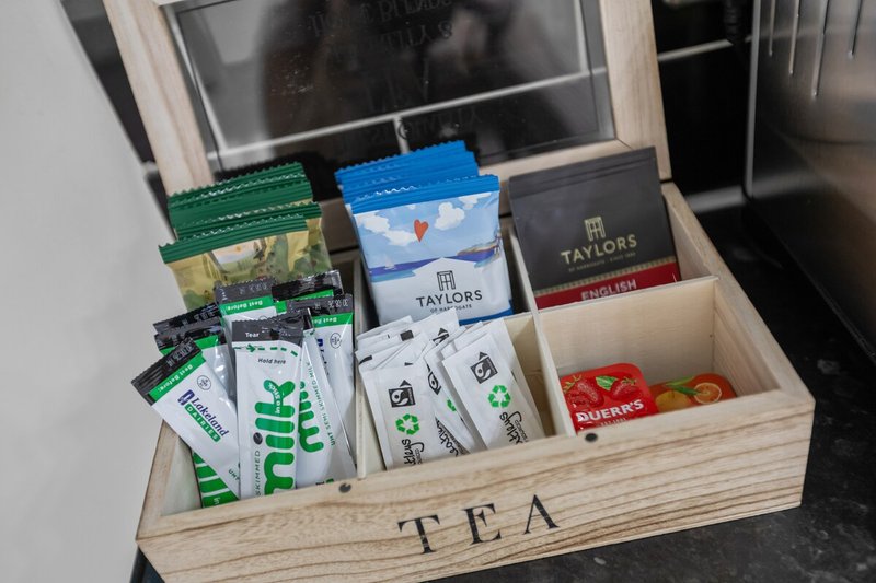 Wooden tea organizer box with compartments containing various tea boxes and packets