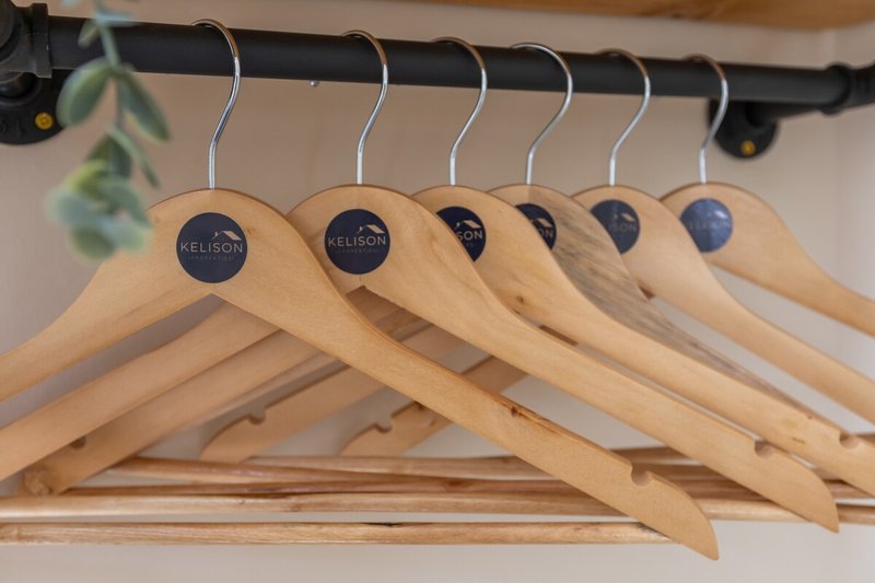 Wooden coat hangers with metal hooks hanging on black rail