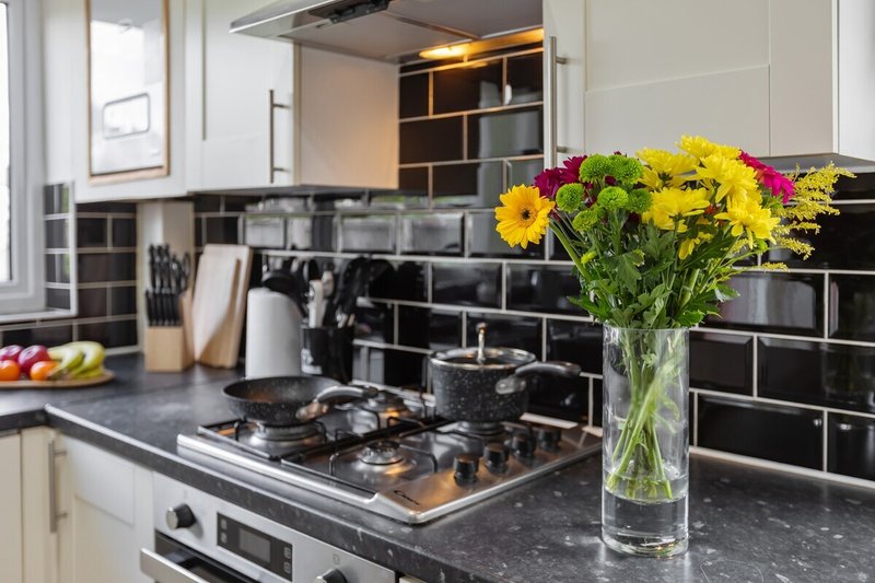 Modern kitchen with black subway tile backsplash, gas cooktop, and yellow flowers in a vase