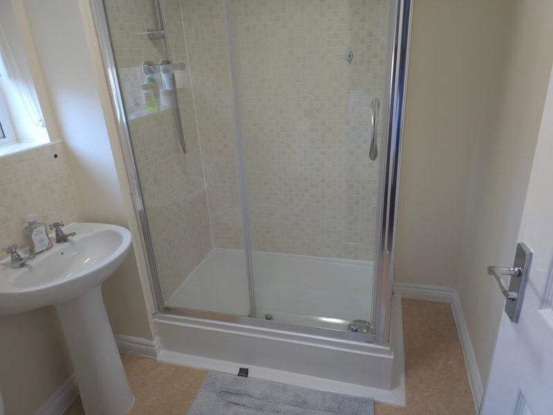 Modern bathroom with pedestal sink, glass-enclosed shower enclosure and tiled walls