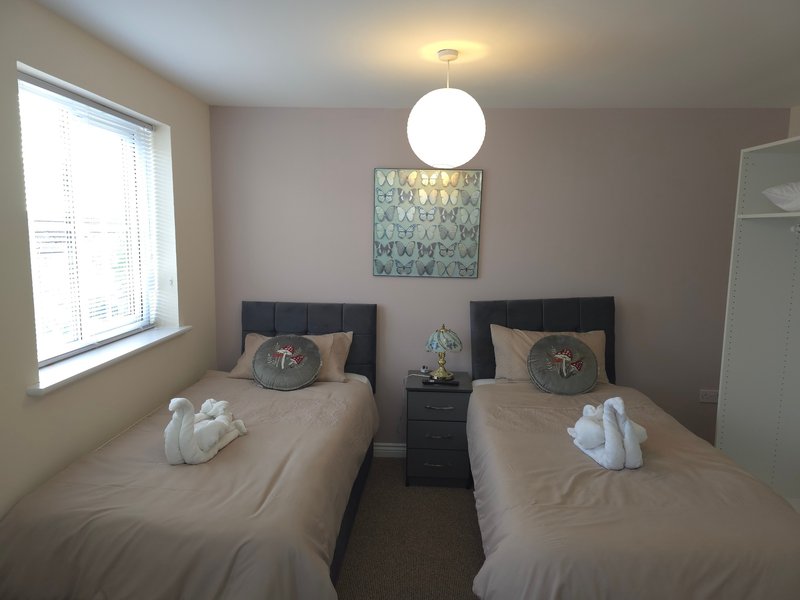 Twin bedroom with two single beds, pendant light, window and wall art