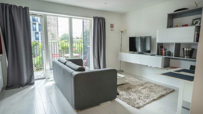 Modern living room with grey sofa, TV unit, balcony doors and grey curtains