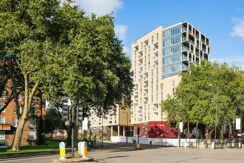 Modern apartment building exterior with trees, street view and blue sky