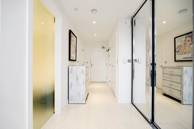 Modern bathroom hallway with marble vanity, mirrored doors, yellow accent wall and recessed lighting