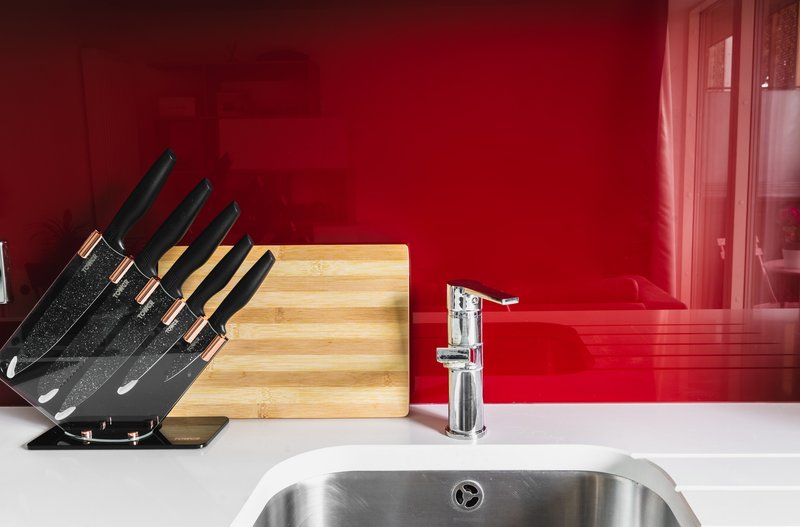 Modern kitchen counter with stainless steel sink, knife block, cutting board and chrome tap