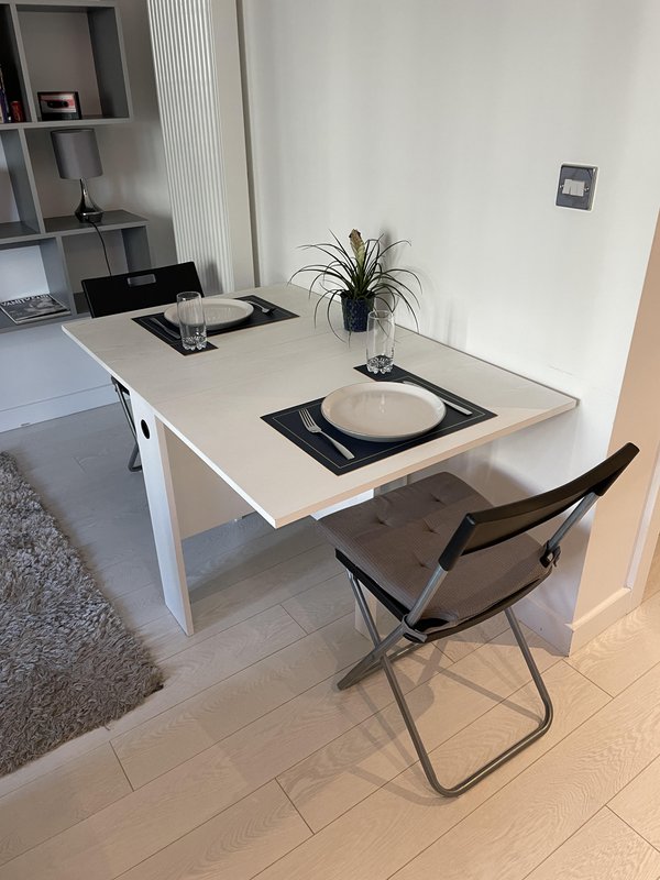 Modern workspace with white desk, black chair, potted plant and place setting