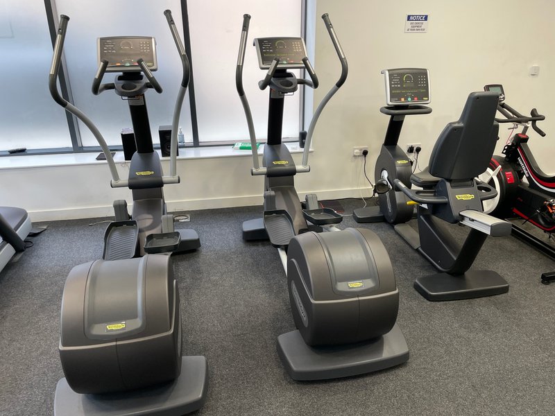 Modern gym room with cardio equipment including elliptical machines and exercise bikes