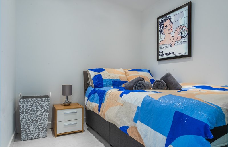 Bedroom with blue and beige checkered bedding, wooden nightstand, and framed wall art