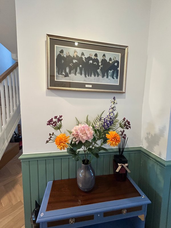 Hallway with framed artwork, blue painted console table, flower arrangement and decorative items