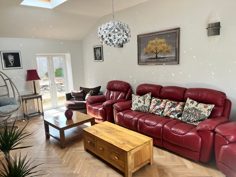 Bright living room with red leather sofa, wooden coffee table, pendant light and framed artwork on walls