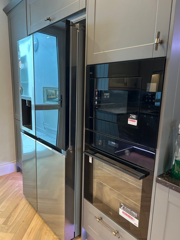 Modern kitchen with stainless steel refrigerator, built-in oven, and cream cabinetry