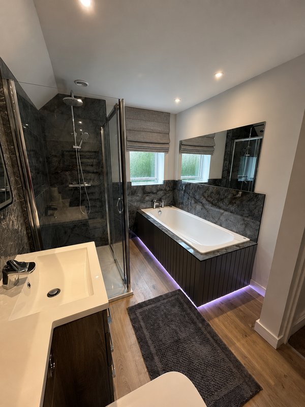 Modern bathroom with double sink, black and white tiling, shower cubicle and bathtub with purple lighting