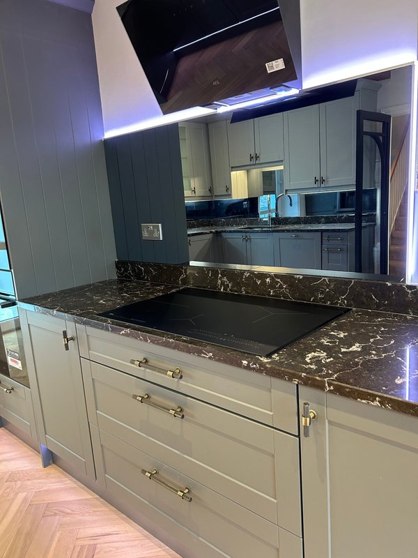 Modern kitchen with white cabinetry, black marble countertop, island, and blue accent lighting