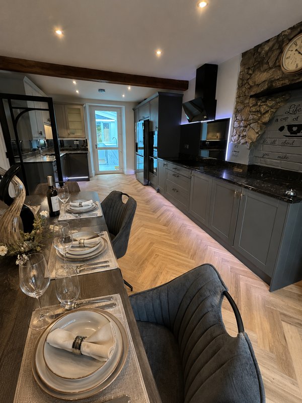 Modern open-plan kitchen and dining area with grey cabinetry, island seating, and contemporary lighting