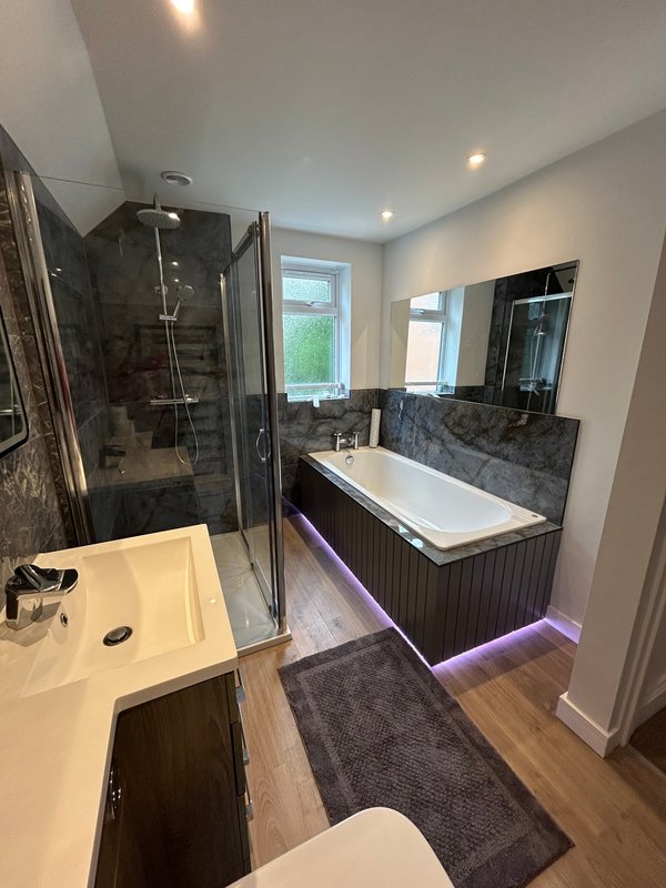Modern bathroom with walk-in shower, freestanding bathtub, dual sinks and purple accent lighting