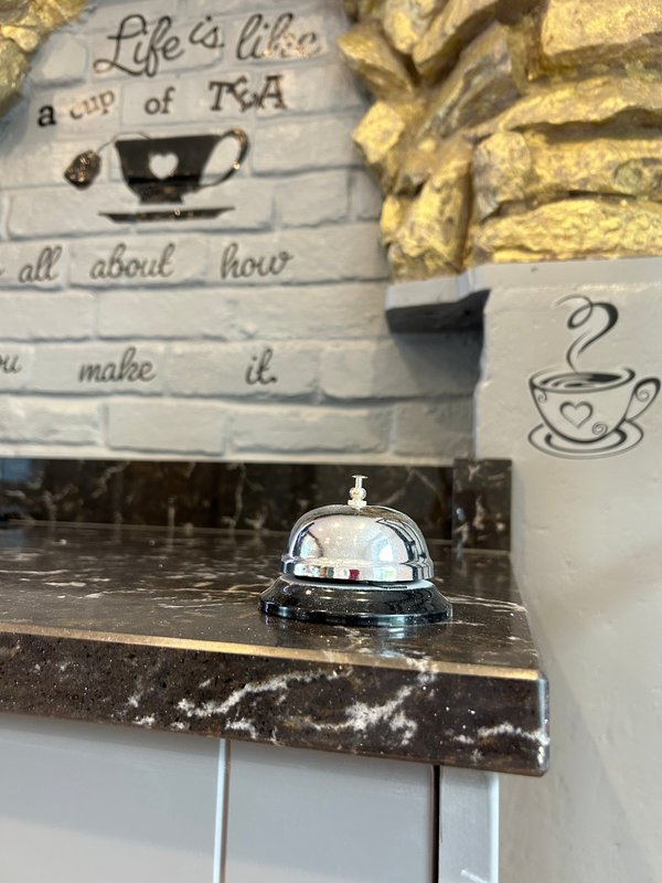 Kitchen counter with decorative tea sign, service bell, and mug artwork on wall