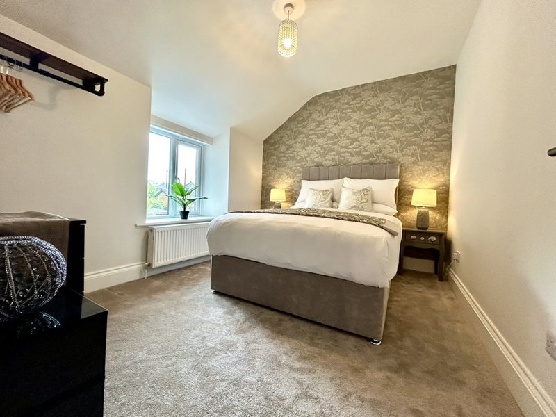 Modern bedroom with double bed, patterned accent wall, bedside lamps and window