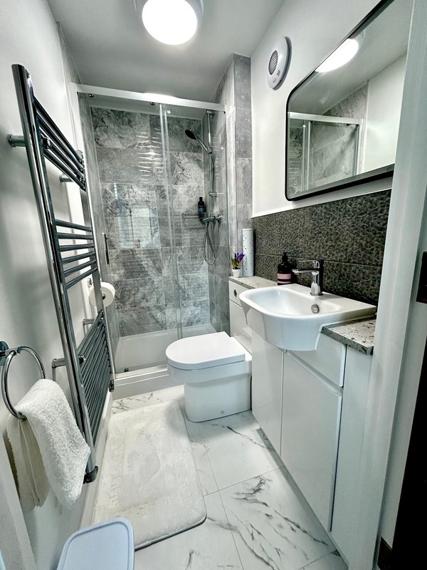 Modern bathroom with white basin, toilet, shower enclosure and heated towel rail