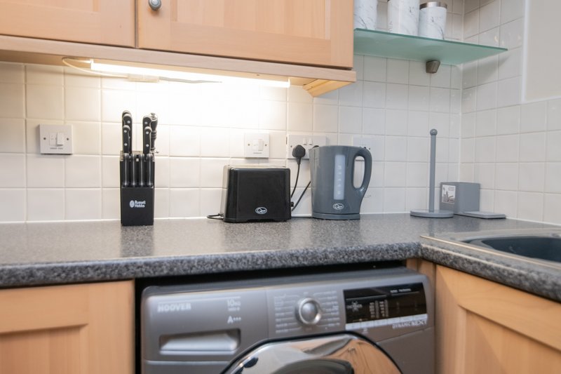 Modern kitchen with wooden cabinets, granite countertop, appliances and kettle