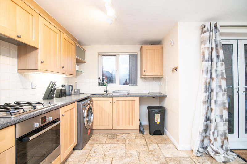 Kitchen with wooden cabinets, gas stove, sink, and tiled flooring