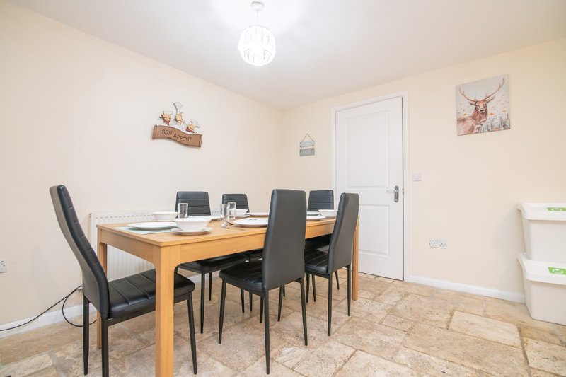 Dining room with wooden table, black chairs, white door and cream walls