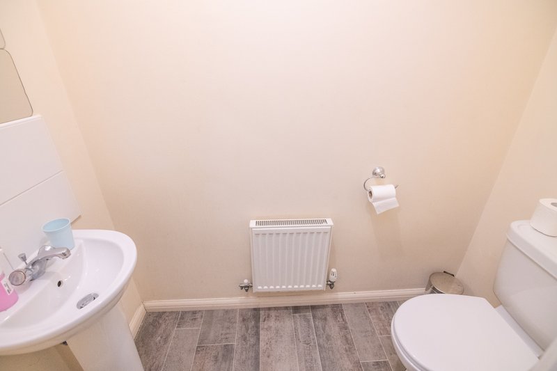 Small bathroom with sink, toilet, radiator and wood-effect flooring