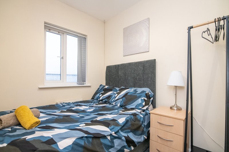 Bedroom with double bed, blue patterned bedding, wooden nightstand, and window with sea view