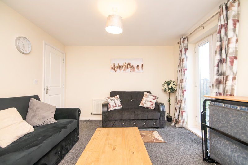 Bright living room with two grey sofas, wooden coffee table, and patterned curtains
