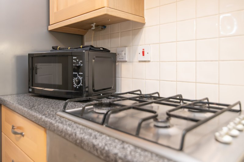 Kitchen countertop with gas hob, microwave, and wooden cabinets