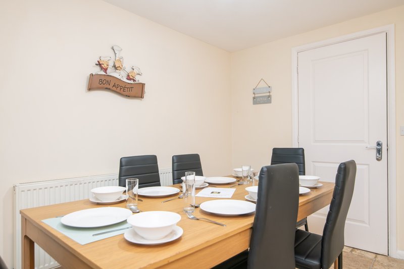 Dining room with wooden table, four black chairs, place settings and white door