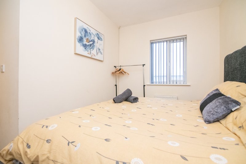 Bedroom with double bed, patterned bedding, blue wall art, window with blinds
