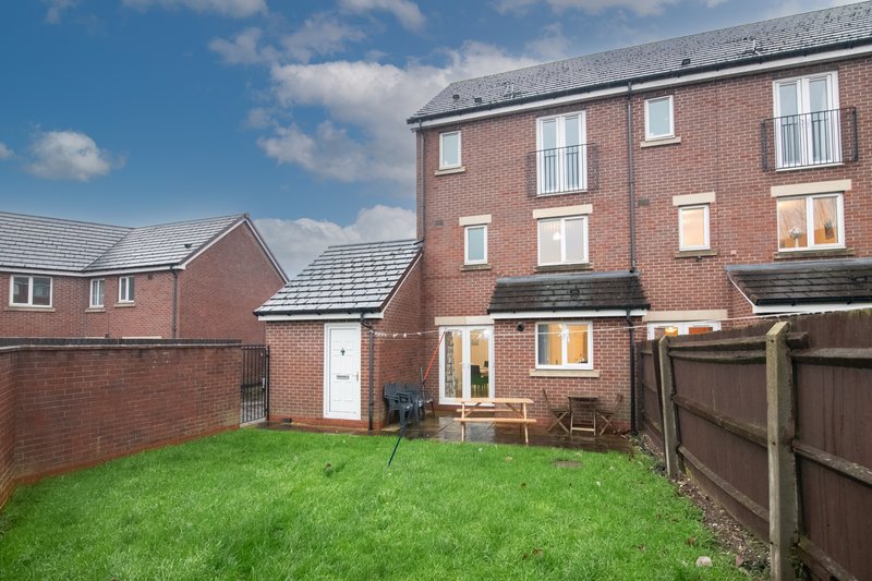 Brick townhouse with rear garden, patio doors, and wooden fence