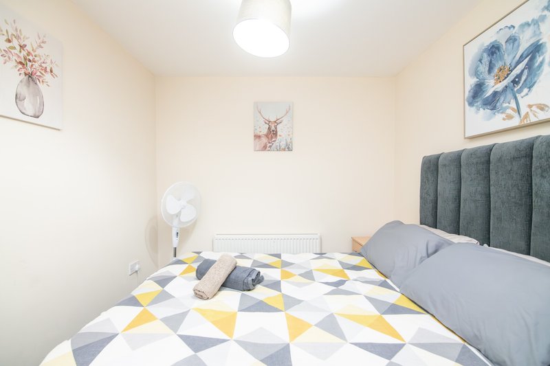 Modern bedroom with double bed, geometric patterned duvet, upholstered headboard, and wall art